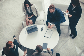 A group of people in suits sitting around a table and working on a design engineering project.