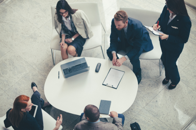 A group of people in suits sitting around a table and working on a project