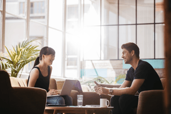 A man and woman having a friendly conversation around a coffee table.