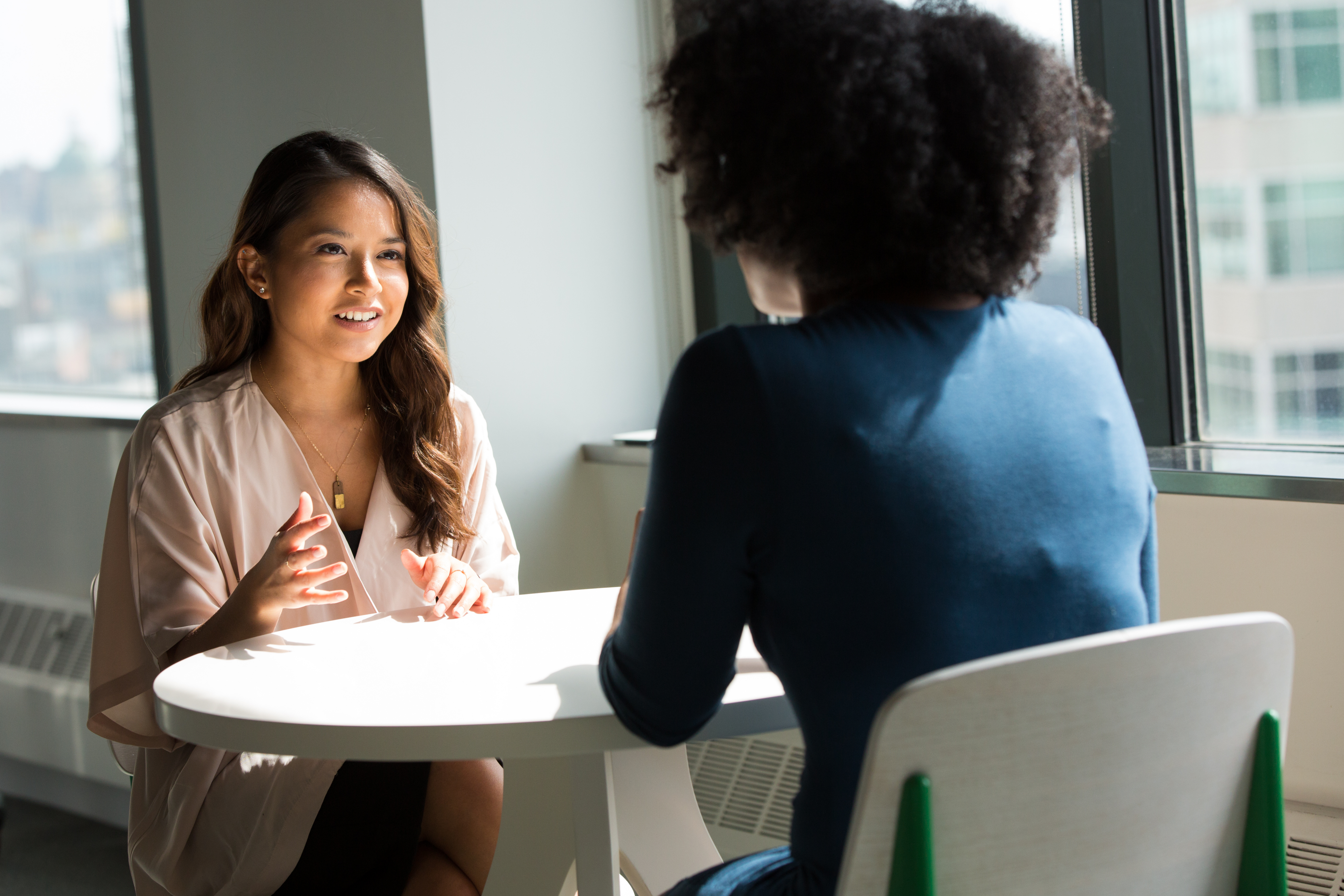 Two women sitting at a table together, having a conversation