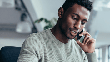 Man speaking on a cellphone in an office.