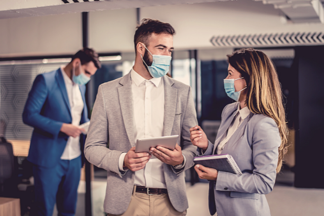 Co-workers chatting wearing masks