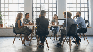 People in an office sitting around a table at a meeting.