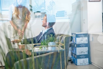 Two people talk in an office about something on a computer screen.