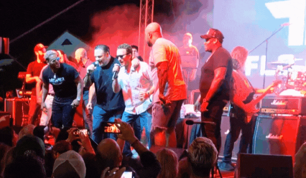 Flo Rida on stage with a large group of people singing at a concert