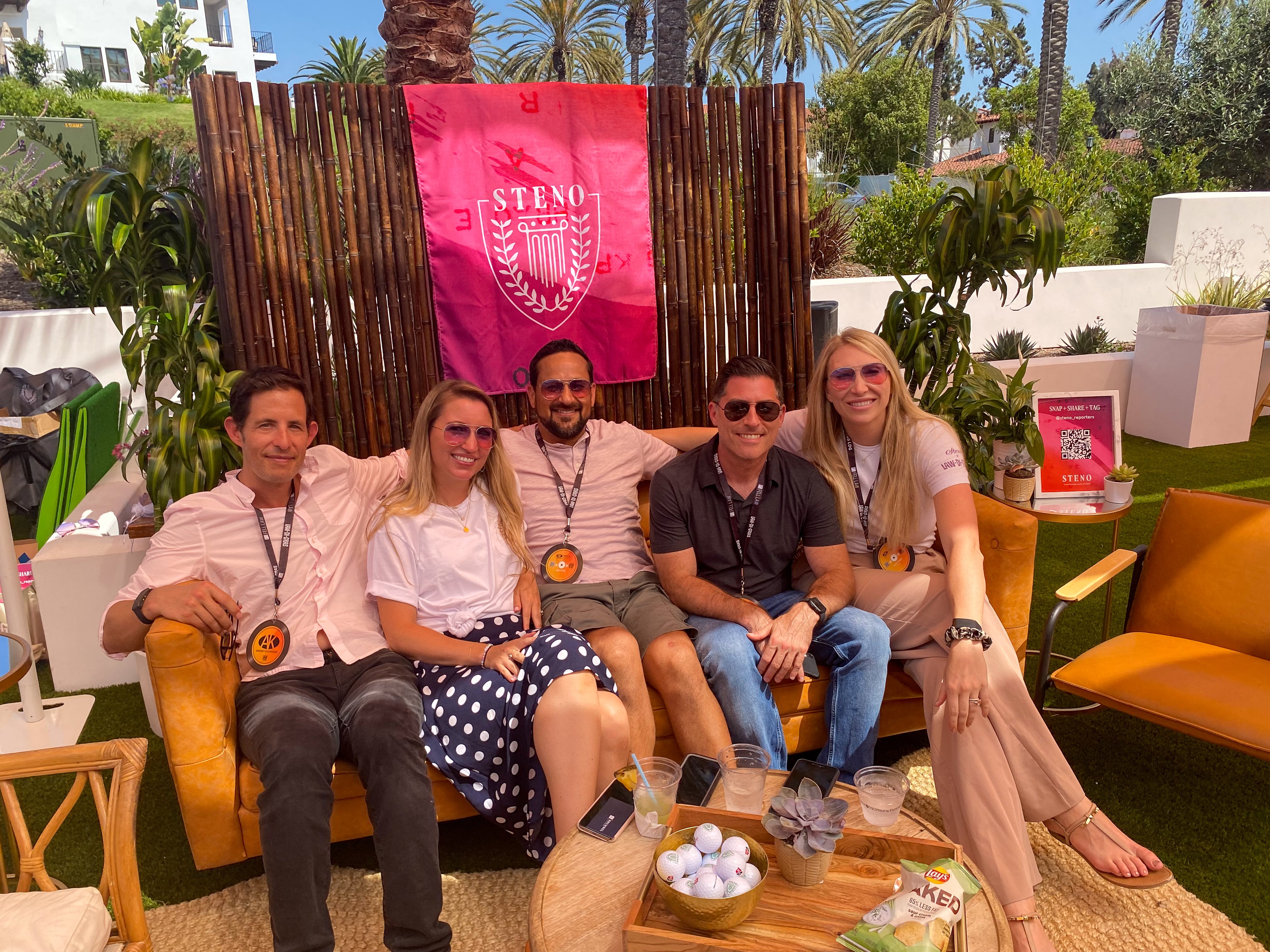 A group shot of Team Steno, including Leann, sitting on a couch at their booth for Law-di-Gras 2021.