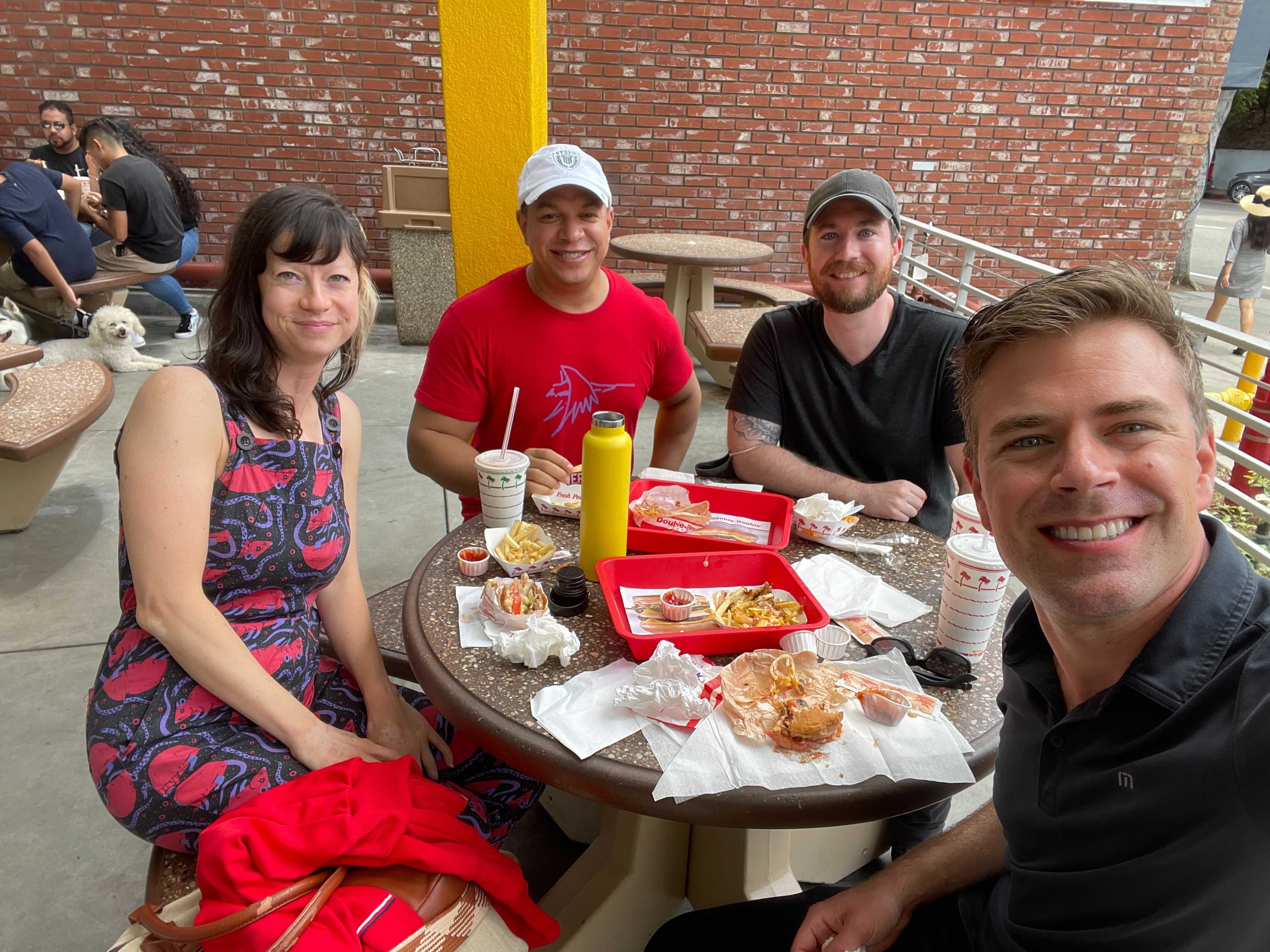 Four people at a picnic table outside of In and Out 