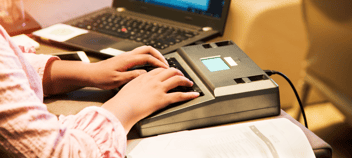 A header image featuring a court reporter's hands on a stenography machine.