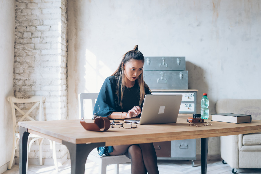 Woman working on a laptop at a desk.